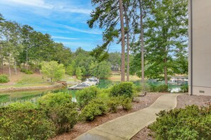 A lakeside view with boats docked, surrounded by dense trees and a clear sky.