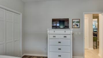 Un dormitorio con un armario blanco, un televisor de pantalla plana y un cuadro en la pared.