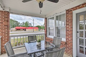 A covered patio with a glass table and chairs, brick walls, and a view of a commercial building. - 'the Rosewood House' 3 Mi to Downtown Columbia! (Columbia)