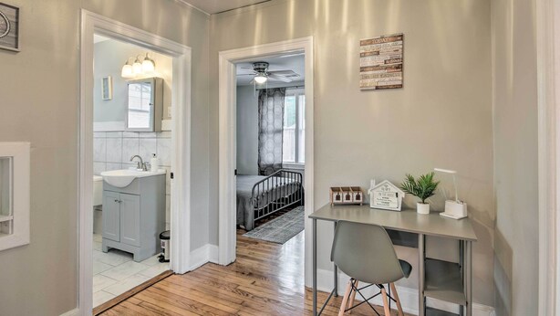 Pasillo con lavamanos, espejo y una mesa con una silla. Una escalera conduce a otra habitación.