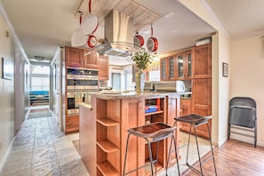 A kitchen with wooden cabinets, a stainless steel range hood, and a bar area with stools. - Surfside Beach Home w/ Resort Perks: Walk to Beach (Murrells Inlet)