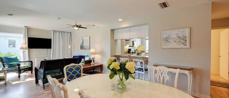 A modern living room with a dining table, chairs, and a flat-screen TV.