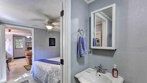 A bedroom with a bed, a bathroom with a sink and mirror, and a hallway leading to another room. - 'the Driftwood Cottage' w/ Patio & Free Wifi! (Quincy)