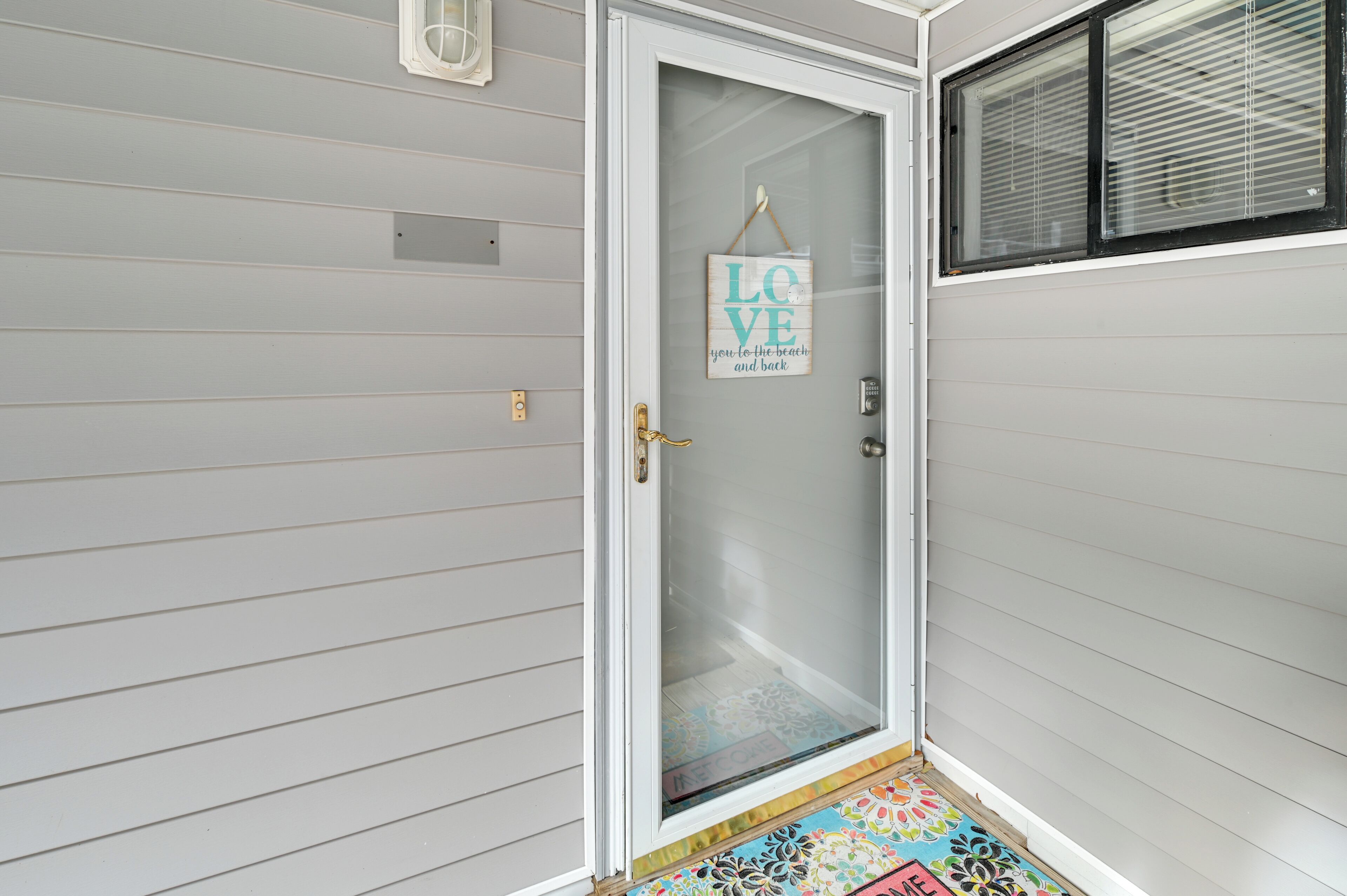 A white door with a frosted glass panel and a hanging sign that reads "LOVE you to the beach and back."