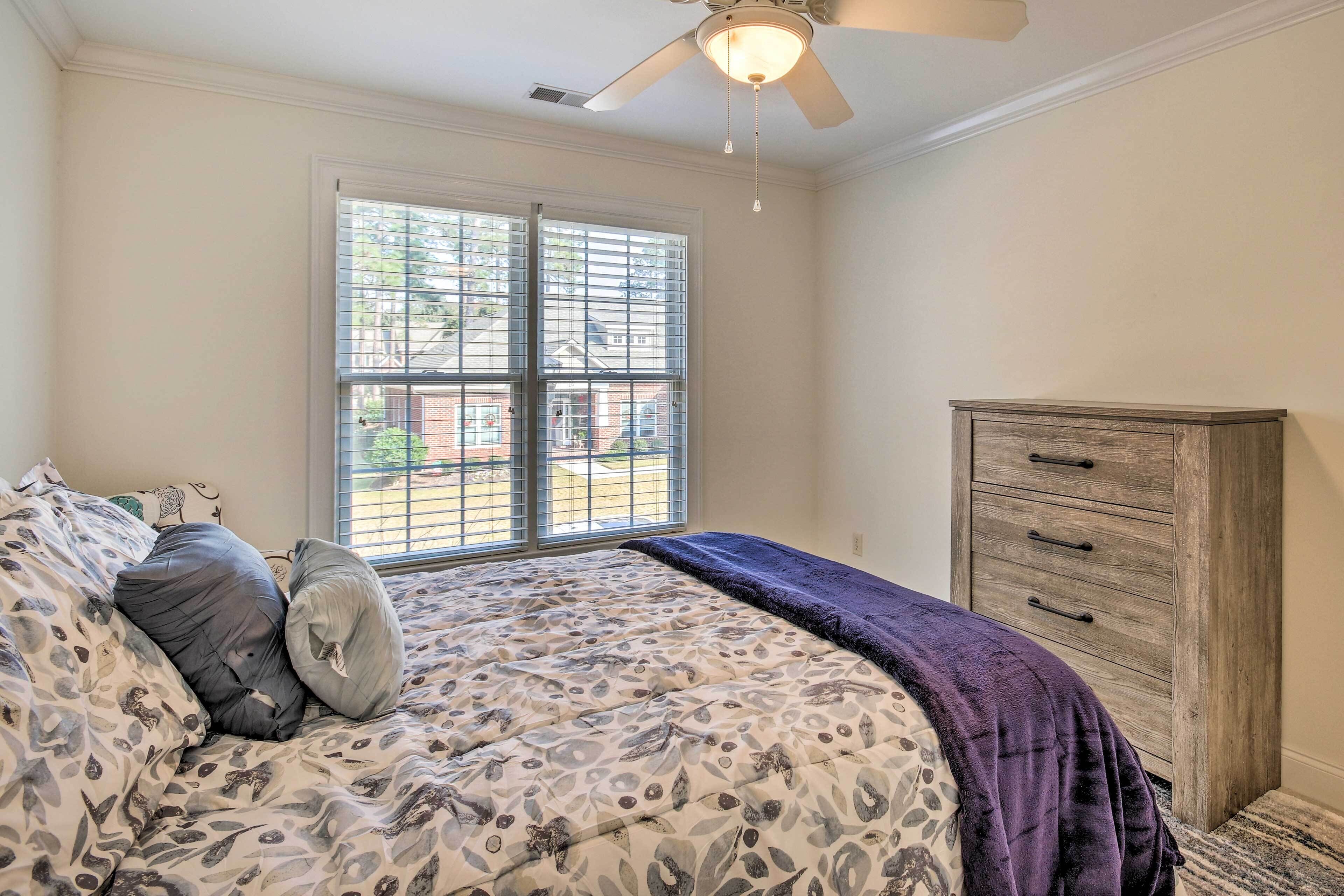 A bedroom with a bed, a dresser, and a window with blinds.
