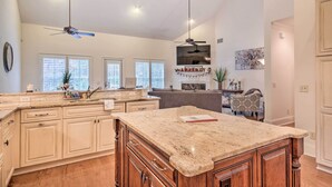 A spacious kitchen with granite countertops, wooden cabinets, and a large island. There are ceiling fans, pendant lights, and a built-in oven. - Upscale Home w/ Poker Room < 1 Mi to Golf! (Aiken)