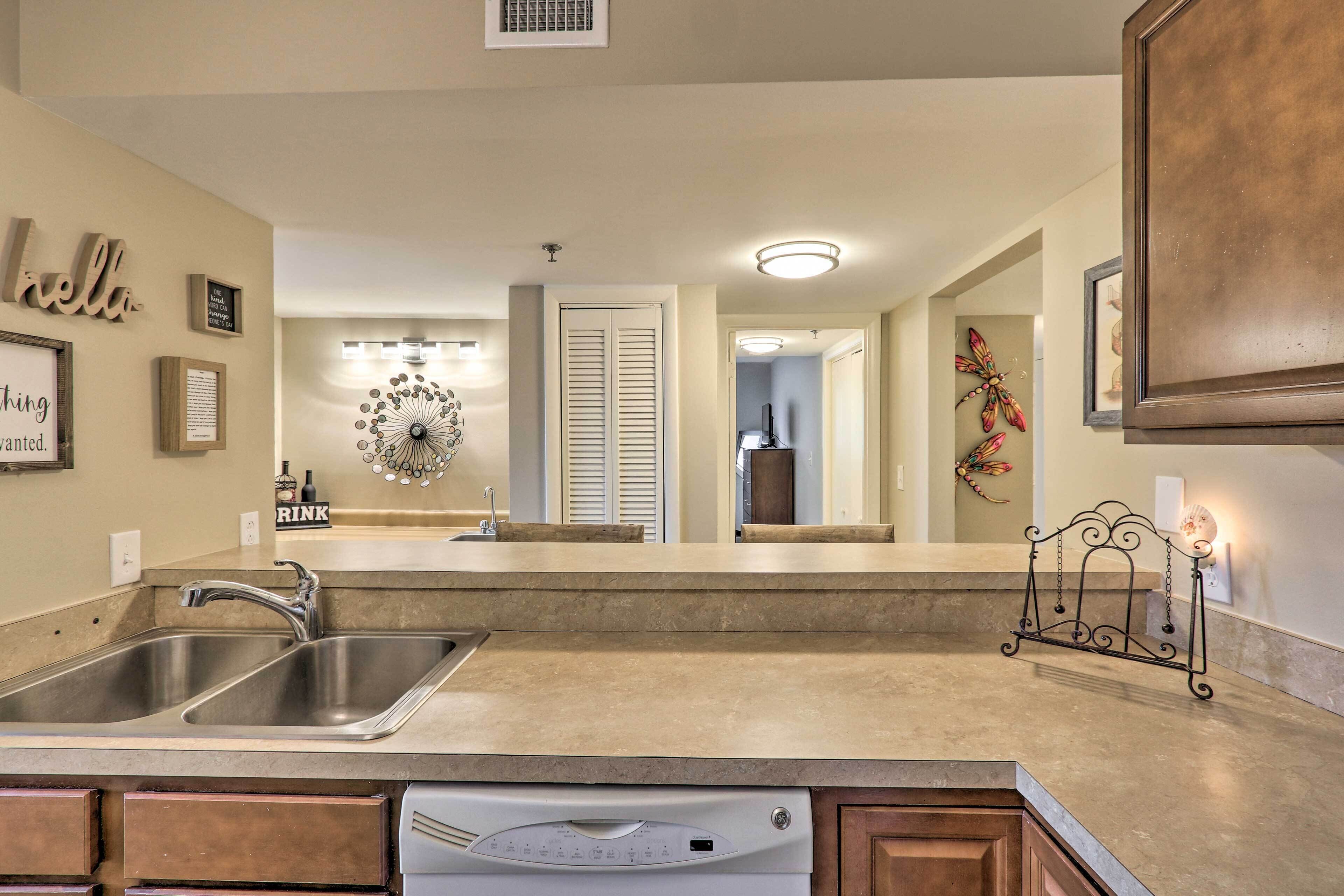 A kitchen with a double sink, a dishwasher, and a decorative mirror.
