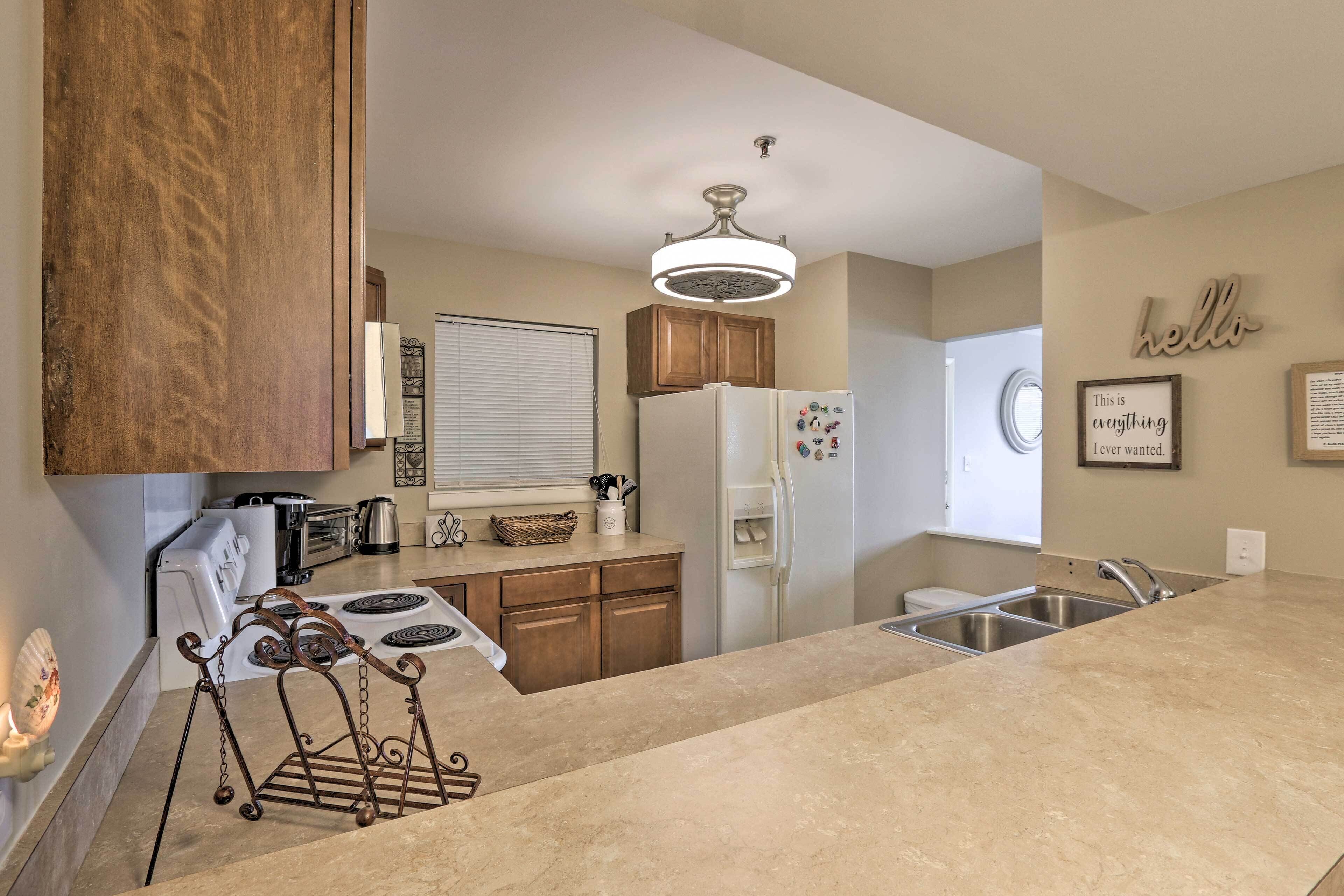 A modern kitchen with wooden cabinets, a white refrigerator, and a stainless steel sink.