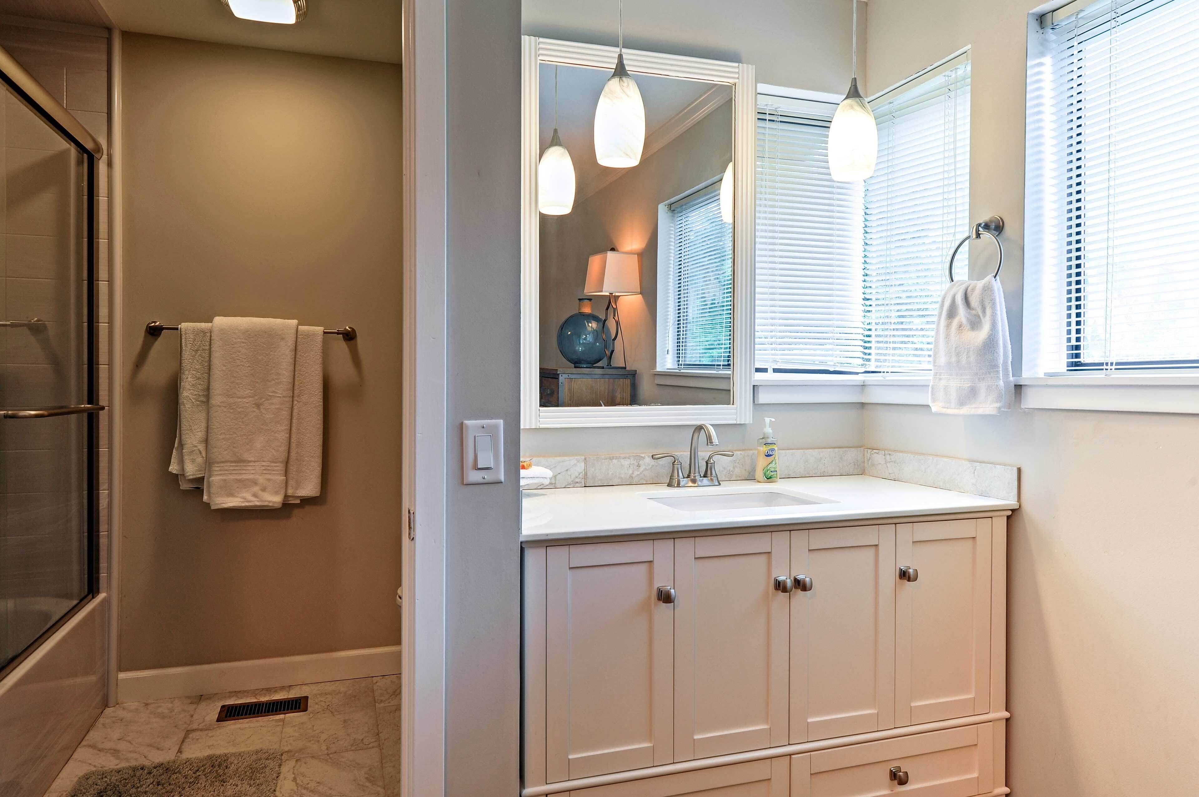 A bathroom with a white vanity, a mirror, and a towel rack.
