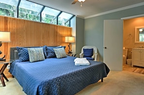 Un dormitorio con una cama grande, cabecera de madera, techo de cristal y baño con espejo y lavabo.