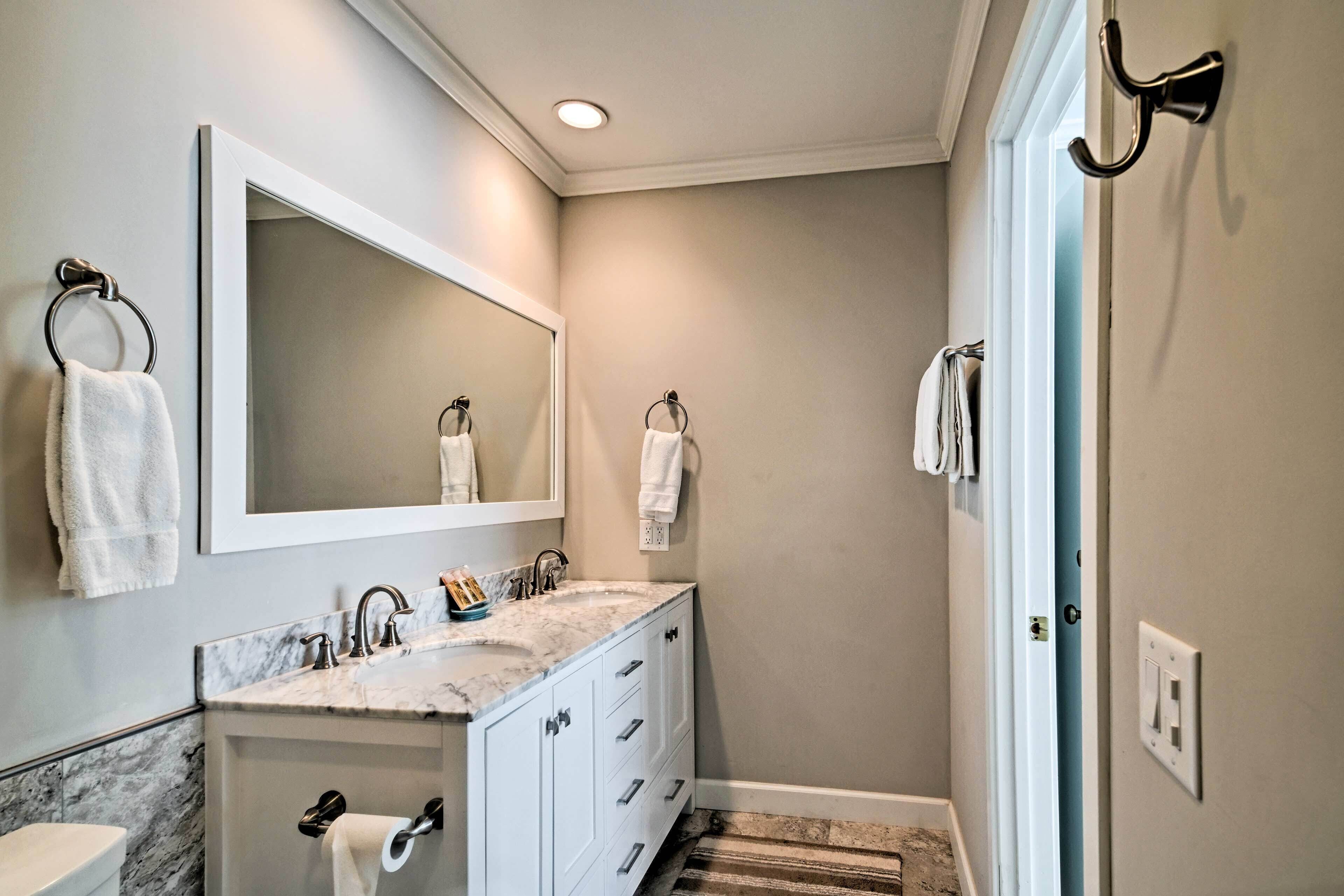 A bathroom with a marble sink, a large mirror, and a towel rack.