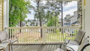 A covered porch with a view of a residential area, featuring a white railing and several chairs. - Pools & Golf, 2 Mi to Beach: Myrtle Beach Condo! (Myrtle Beach)