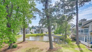 A residential area with multiple houses, a pond, and trees. - Pools & Golf, 2 Mi to Beach: Myrtle Beach Condo! (Myrtle Beach)