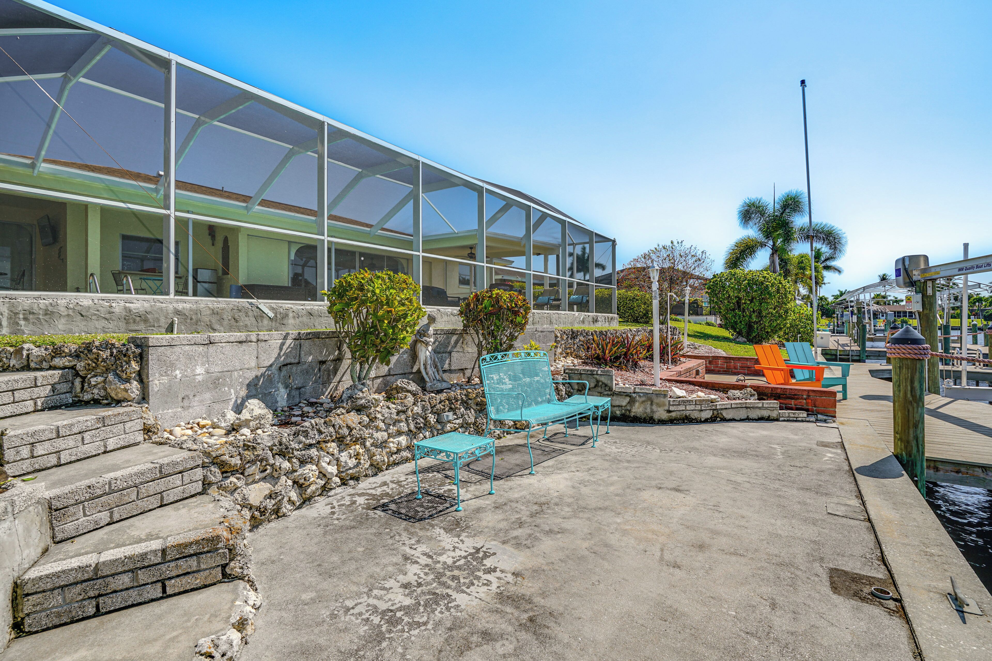 A covered outdoor area with steps leading up to a building, outdoor seating, and a view of the water.