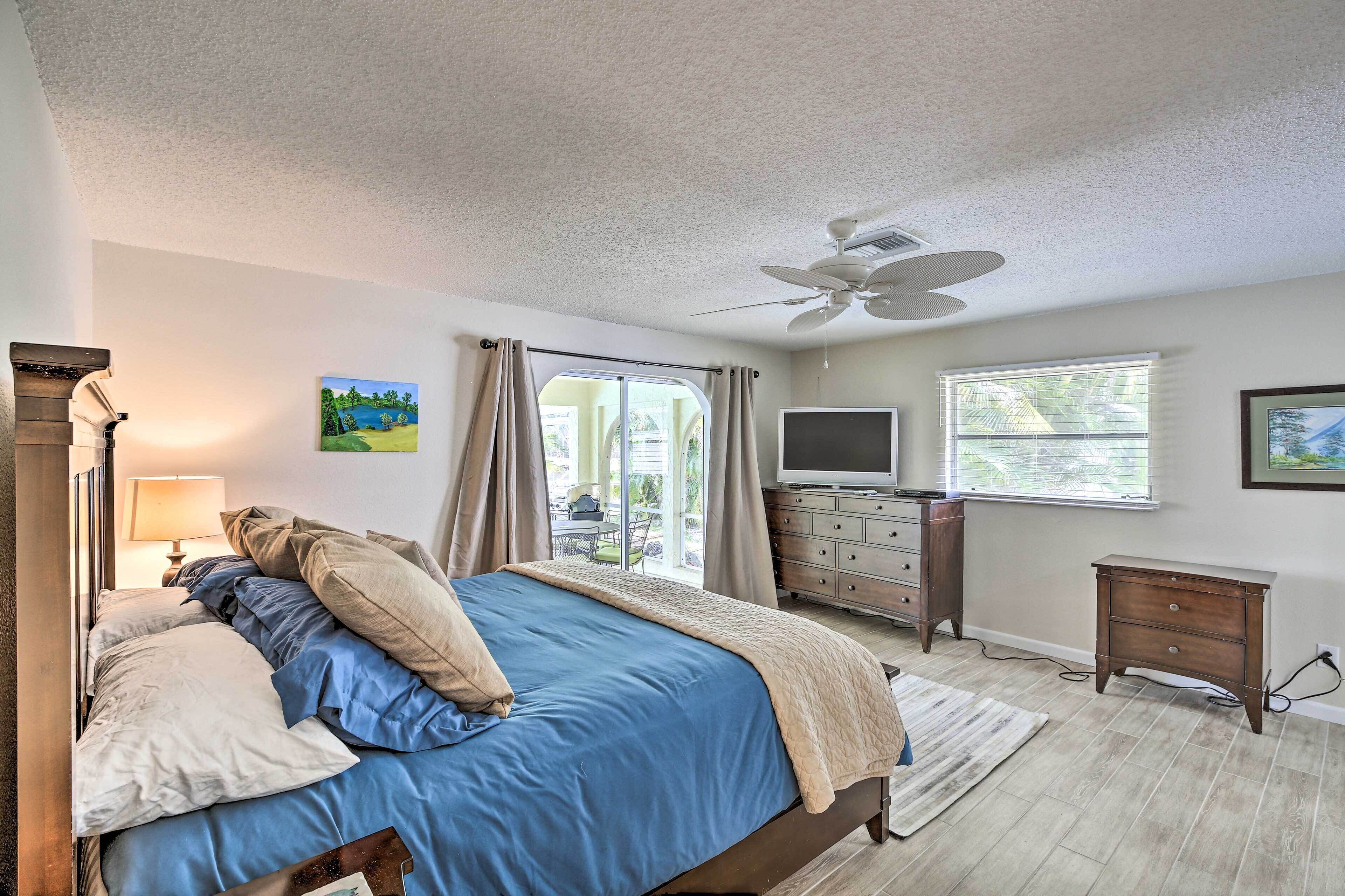A bedroom with a bed, a TV, a dresser, and a ceiling fan.