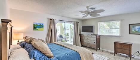 A bedroom with a bed, a TV, a dresser, and a ceiling fan.