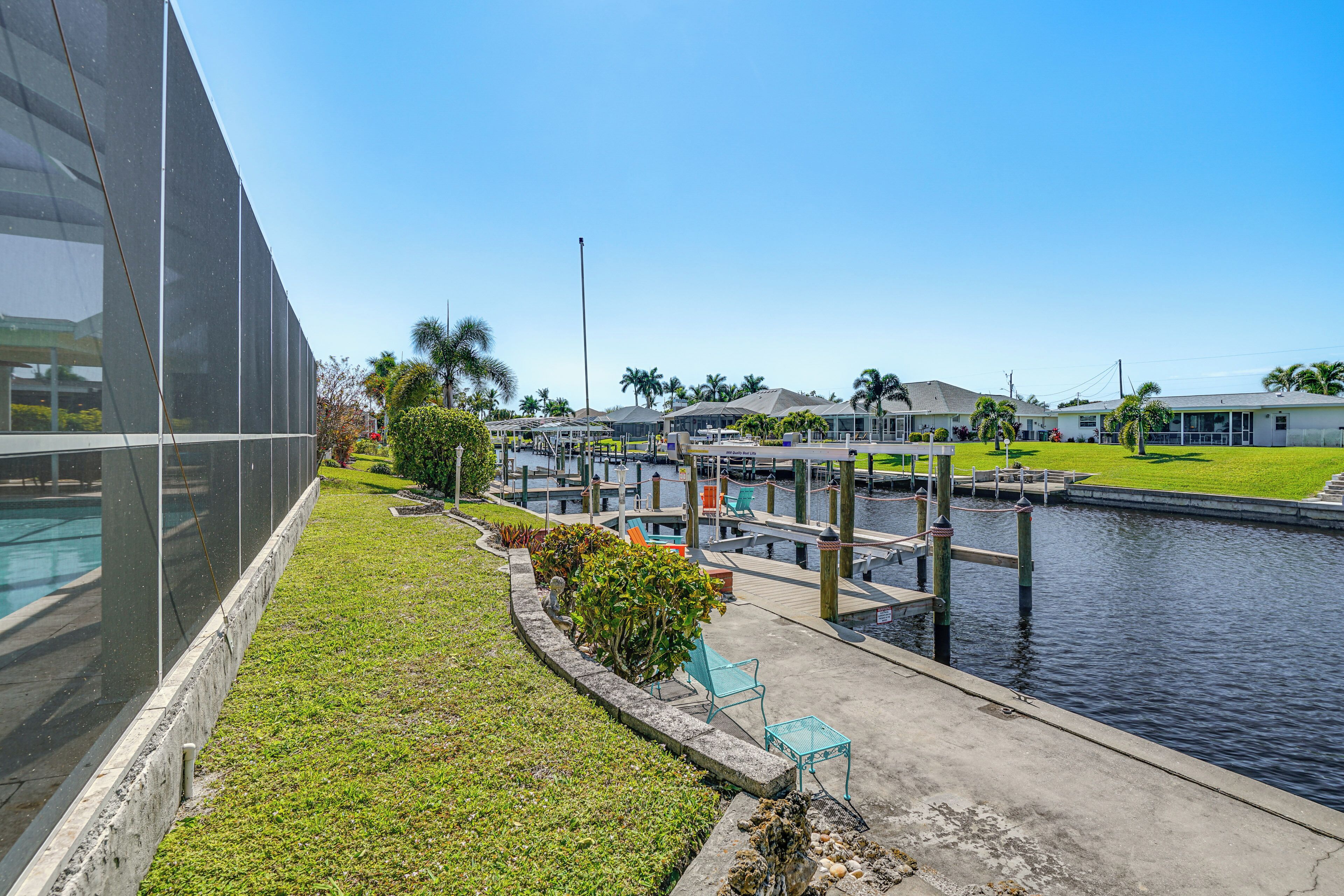 A marina with docked boats, a grassy area with a small garden, and a modern building with large windows.