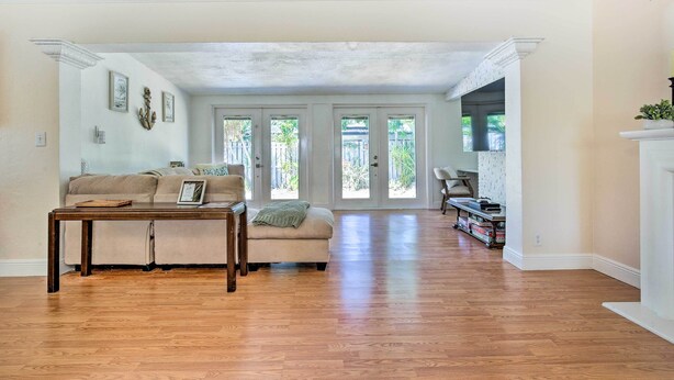 A spacious living room with hardwood flooring, a beige sofa, a wooden coffee table, and a fireplace. - Vacation Rental w/ Private Pool in Wilton Manors (Wilton Manors)