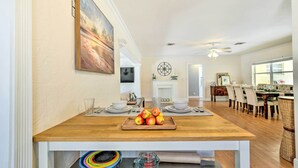 A spacious dining area with a wooden table, a fruit centerpiece, and a view into the living room. - Vacation Rental w/ Private Pool in Wilton Manors (Wilton Manors)