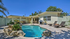 A swimming pool surrounded by a paved patio with lounge chairs and a small building with a door and window. - Vacation Rental w/ Private Pool in Wilton Manors (Wilton Manors)