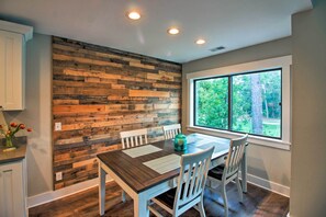 A dining area with a wooden wall, a window with a view of trees, and a table with chairs. - Villa w/ Golf Course Views, Walk to Harbour Town! (Hilton Head Island)