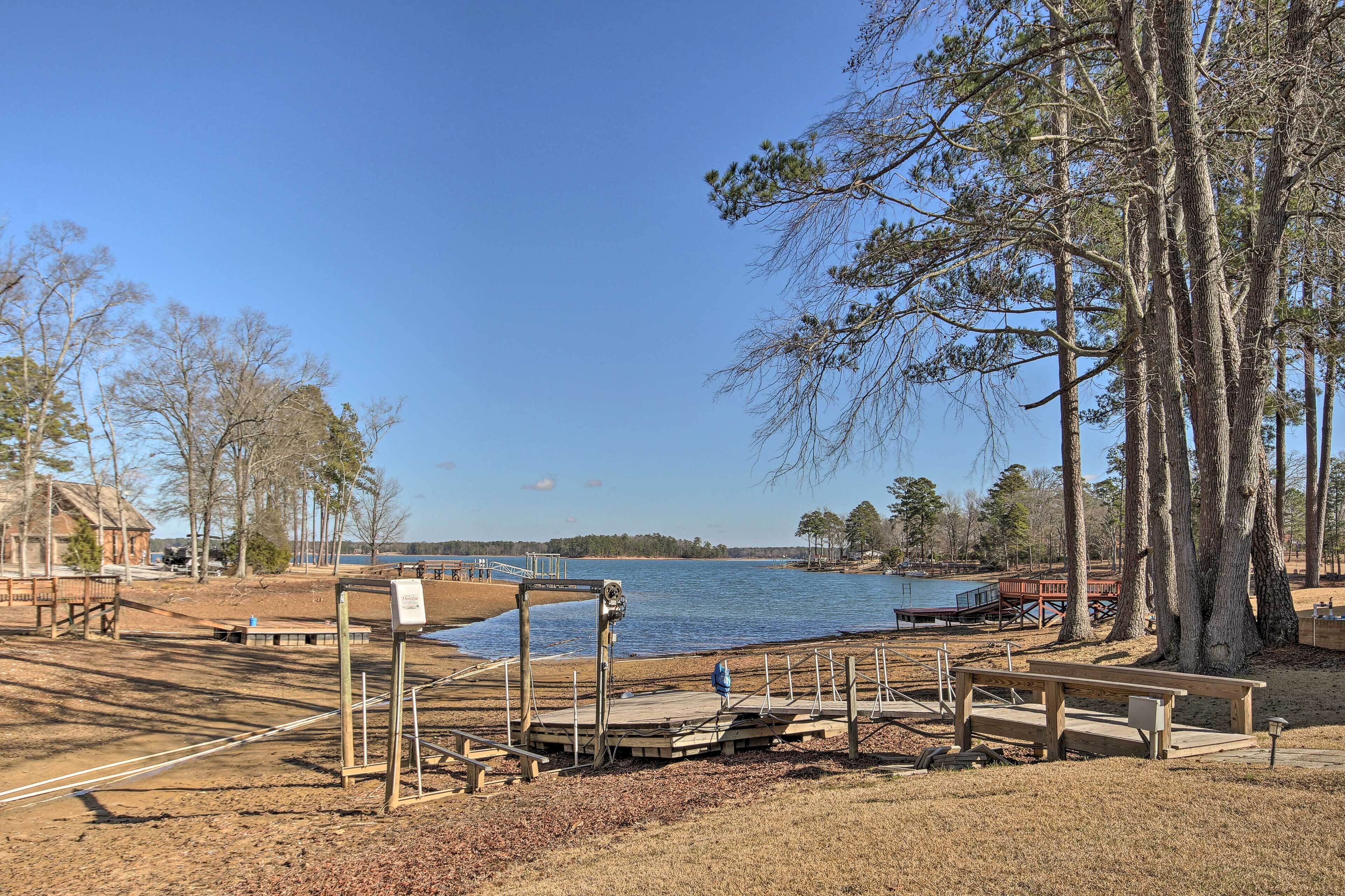 En park vid sjön med en träbrygga, picknickbord och en utkiksplattform.