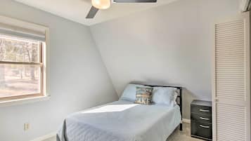 A bedroom with a bed, a ceiling fan, a window, and a wardrobe.