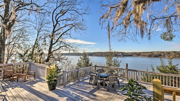 Una terraza de madera con mobiliario exterior y vistas a un lago.