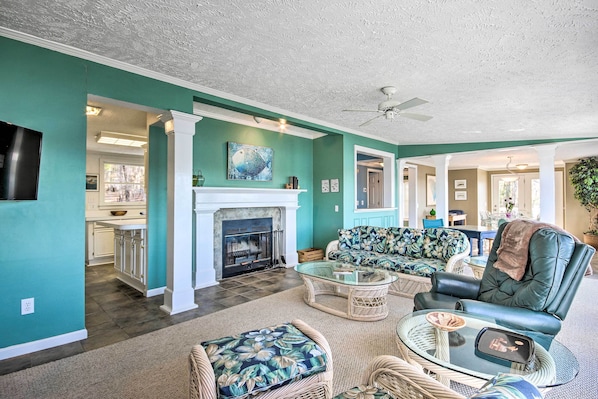 A spacious living room with a fireplace, wicker furniture, and teal walls.
