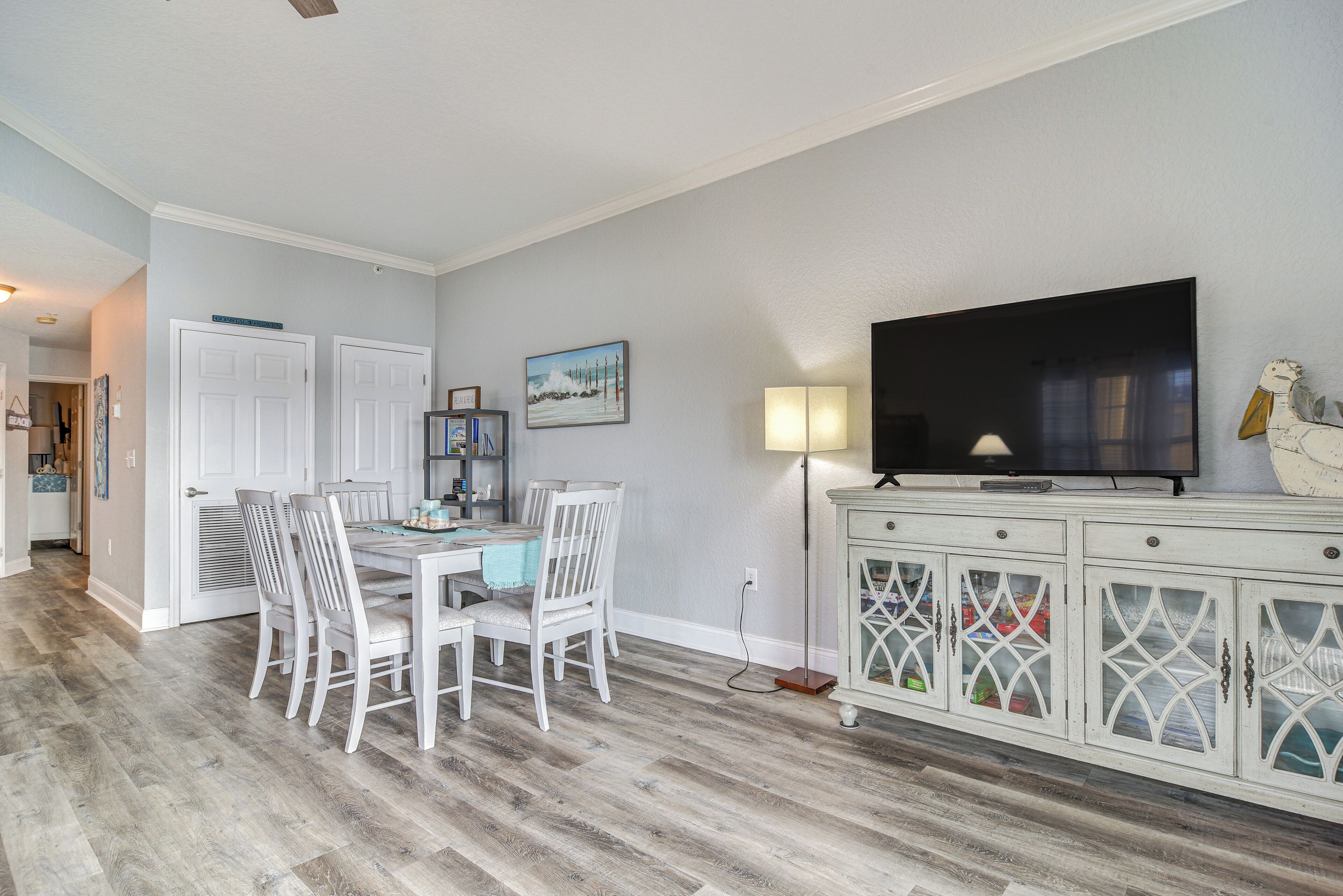 A dining area with a table and chairs, a television, and a cabinet with glass doors.