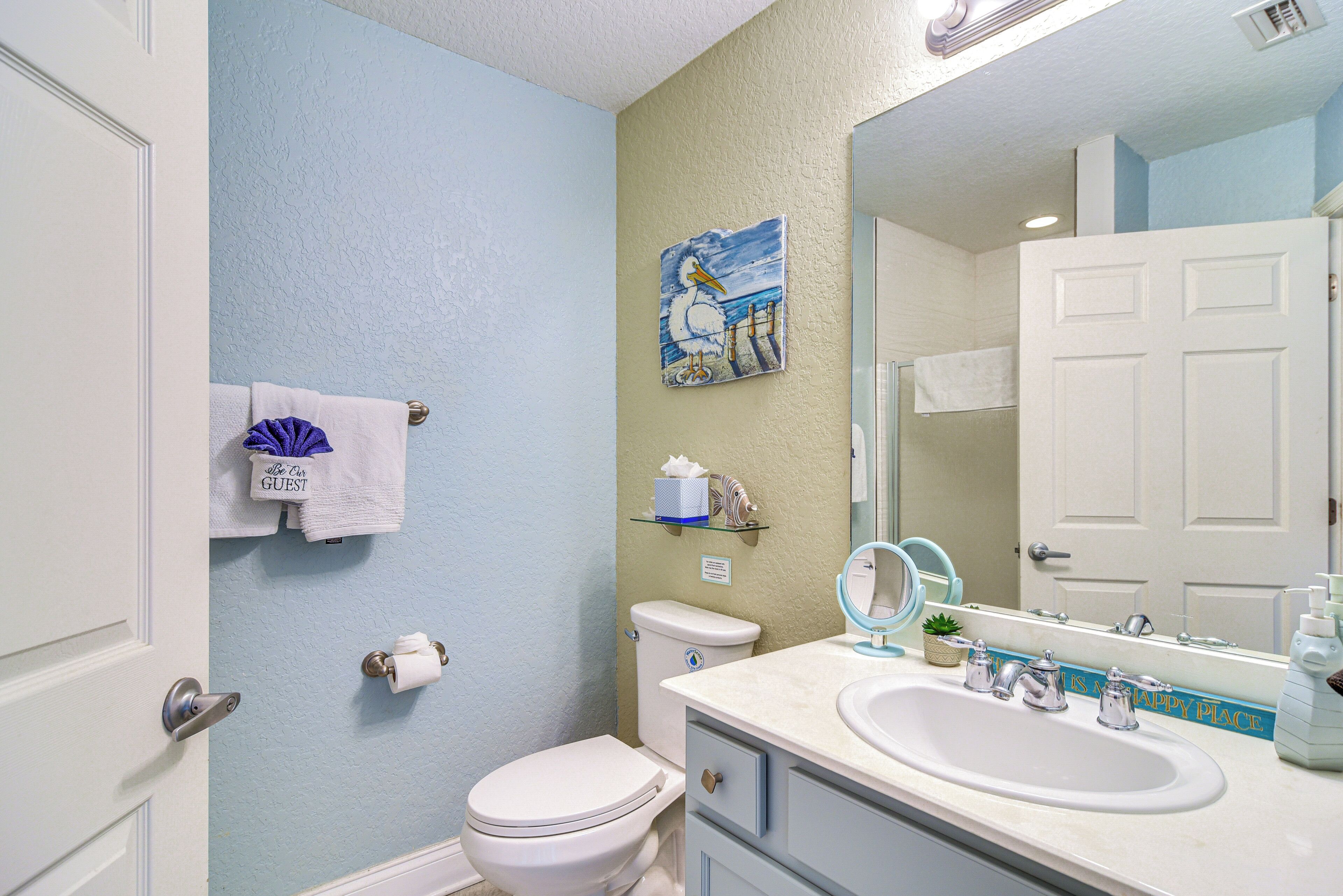 A bathroom with a toilet, sink, and a mirror.