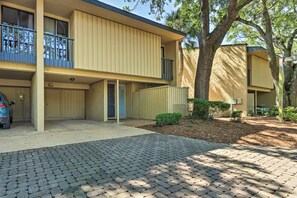 A two-story building with a paved driveway and a car parked in the driveway. - Vintage Hilton Head Island Condo: Steps to Beach! (Hilton Head Island)