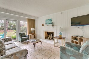 A living room with a fireplace, comfortable seating, and a television. - Vintage Hilton Head Island Condo: Steps to Beach! (Hilton Head Island)
