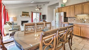 Ein geräumiges Wohnzimmer mit Holzesstisch, bequemen Sitzmöglichkeiten, einem Kamin und einer Küchenzeile mit Holzschränken und einem Kühlschrank.