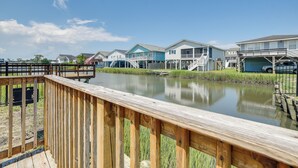 A waterfront property with a wooden deck, houses with balconies, and a clear sky. - Waterfront Home w/ Deck in North Myrtle Beach! (North Myrtle Beach)
