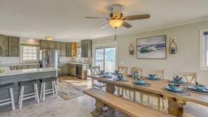 A spacious kitchen with a wooden dining table set for four, a ceiling fan, and a large window. - Waterfront Home w/ Deck in North Myrtle Beach! (North Myrtle Beach)