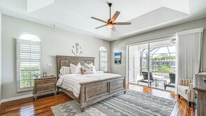 A bedroom with a large bed, a ceiling fan, and a view of the outdoors through a sliding glass door. - Marco Island Home w/ Screened Pool < 1 Mi to Beach (Marco Island)