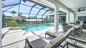 A poolside area with lounge chairs, a pool, and a view of palm trees and houses. - Marco Island Home w/ Screened Pool < 1 Mi to Beach (Marco Island)