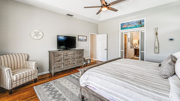 A bedroom with a bed, a television, a ceiling fan, a dresser, and a door leading to another room. - Marco Island Home w/ Screened Pool < 1 Mi to Beach (Marco Island)