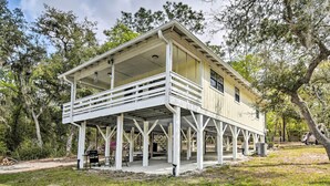 A two-story house with a balcony, surrounded by trees and a grassy yard.