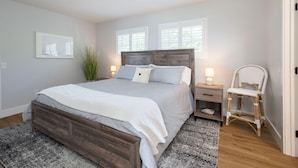A bedroom with a large bed, bedside tables, a chair, and a window.