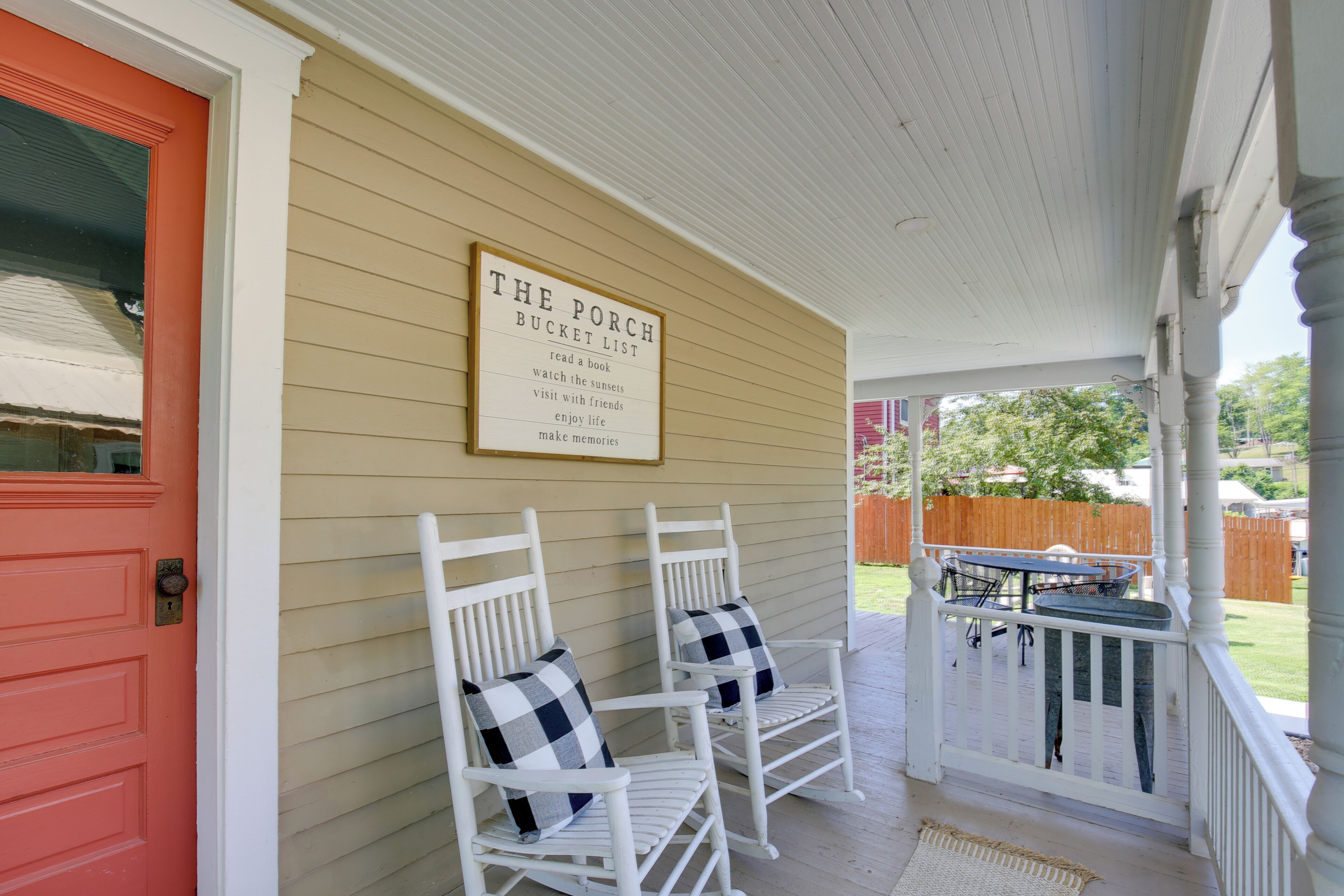 A porch with two white rocking chairs and a sign listing activities like reading a book and visiting friends.