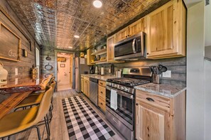 A kitchen with wooden cabinets, a stainless steel stove, and a checkered floor. - The Reubling House - Modern-rustic Cabin! (Defiance)