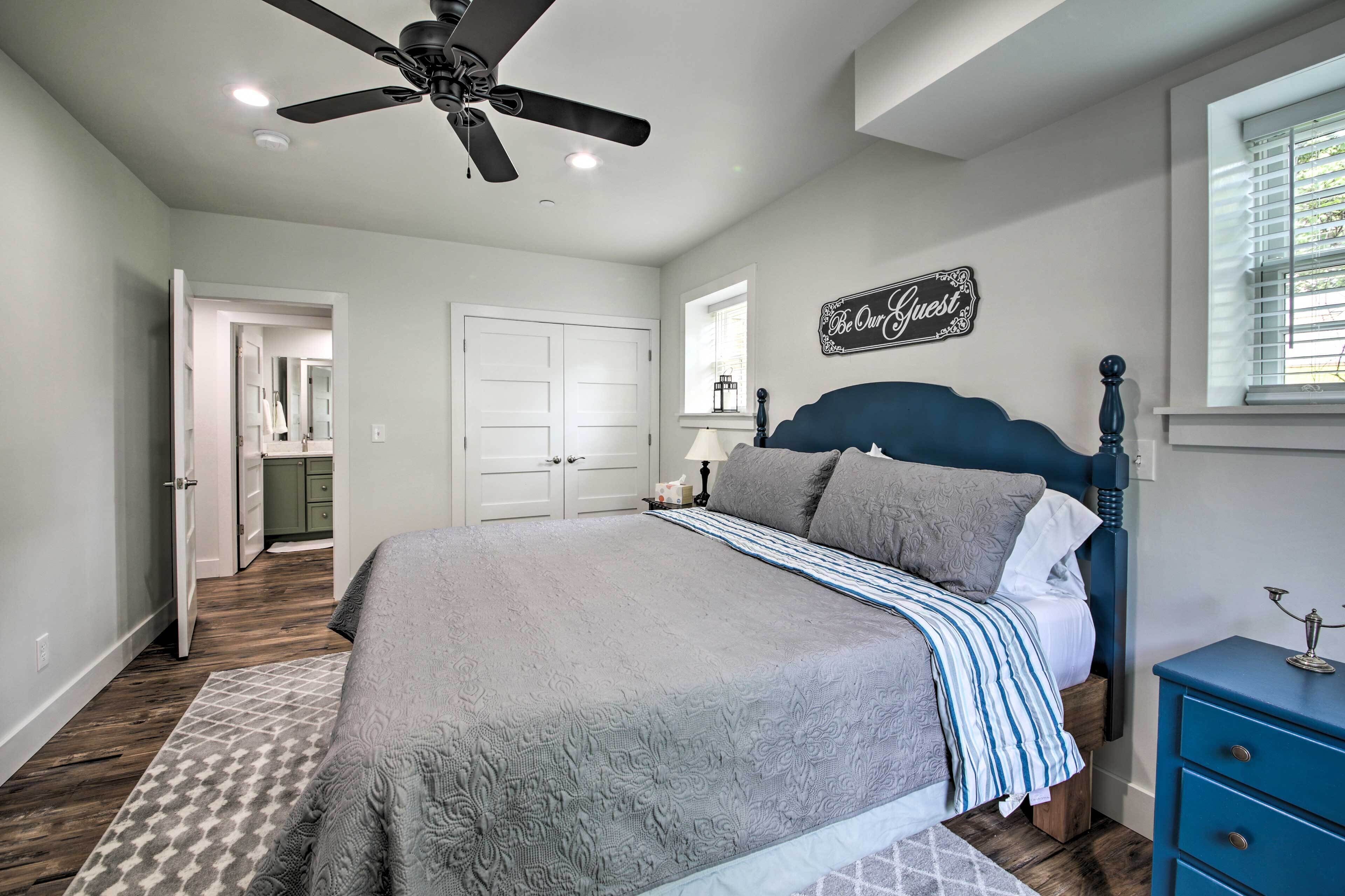 A bedroom with a bed, a ceiling fan, a dresser, and a window with blinds.