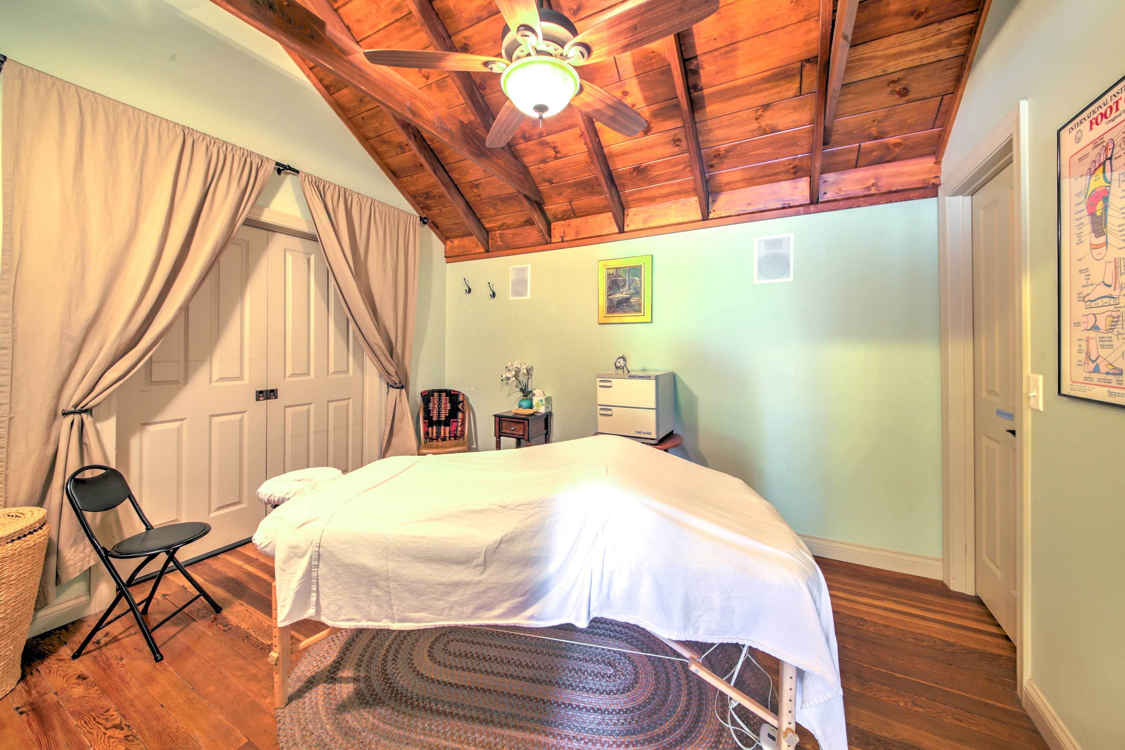 A bedroom with a bed, a chair, a desk, and a ceiling fan.