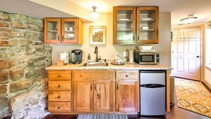 A kitchen with wooden cabinets, a granite countertop, a microwave, a coffee maker, and a refrigerator. - Augusta Studio at Halcyon Spa Bed & Breakfast (Augusta)
