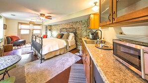 A compact bedroom with a bed, bedside table, and a ceiling fan. Adjacent is a kitchenette with a microwave, sink, and countertop. - Augusta Studio at Halcyon Spa Bed & Breakfast (Augusta)