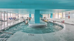 Ein Innenpool mit einer zentralen Fontäne, umgeben von Liegestühlen und einer gefliesten Kante.