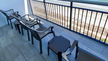 Een balkon met uitzicht op het strand, met een tafel en vier stoelen.