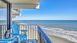 A balcony with blue Adirondack chairs and a view of the ocean. - Beachfront Murrells Inlet Condo w/ Ocean Views (Murrells Inlet)
